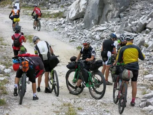 Un gruppo di rider con le bici cariche su uno sterrato nel bosco