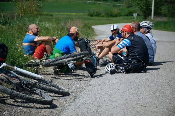 Rider seduti a bordo strada con le bici a terra
