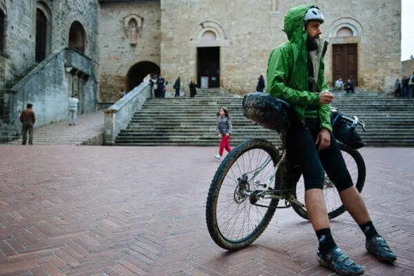 Un rider con la bici carica in una piazza di pietra