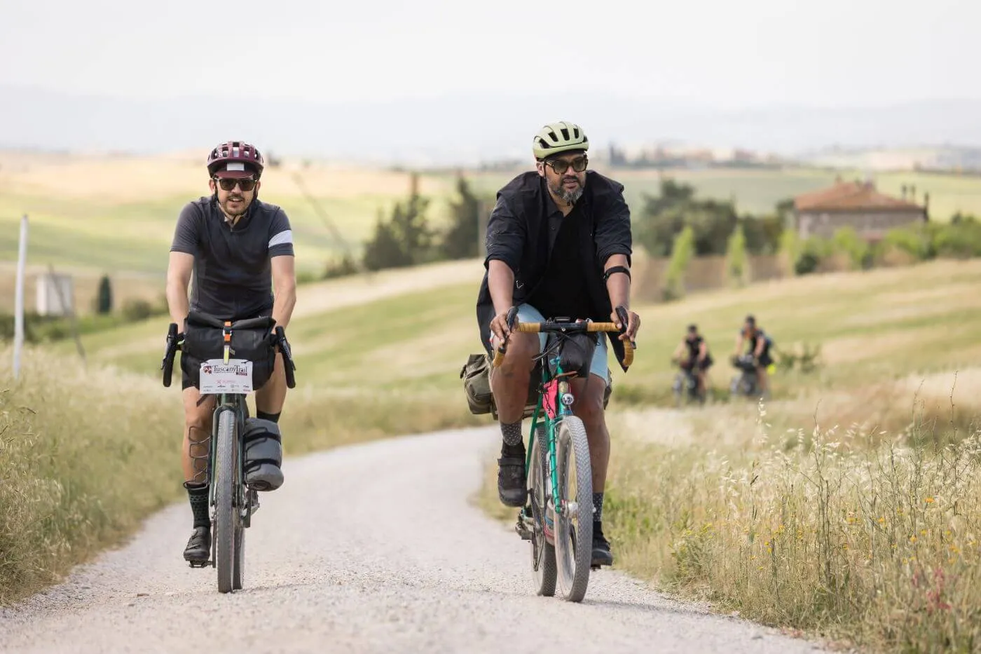Due rider su una strada bianca fra i campi di grano