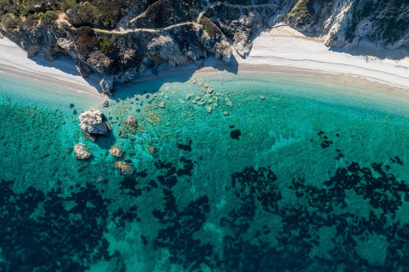 Veduta dall'alto di una spiaggia dell'Isola d'Elba con acqua trasparente e scogli affioranti