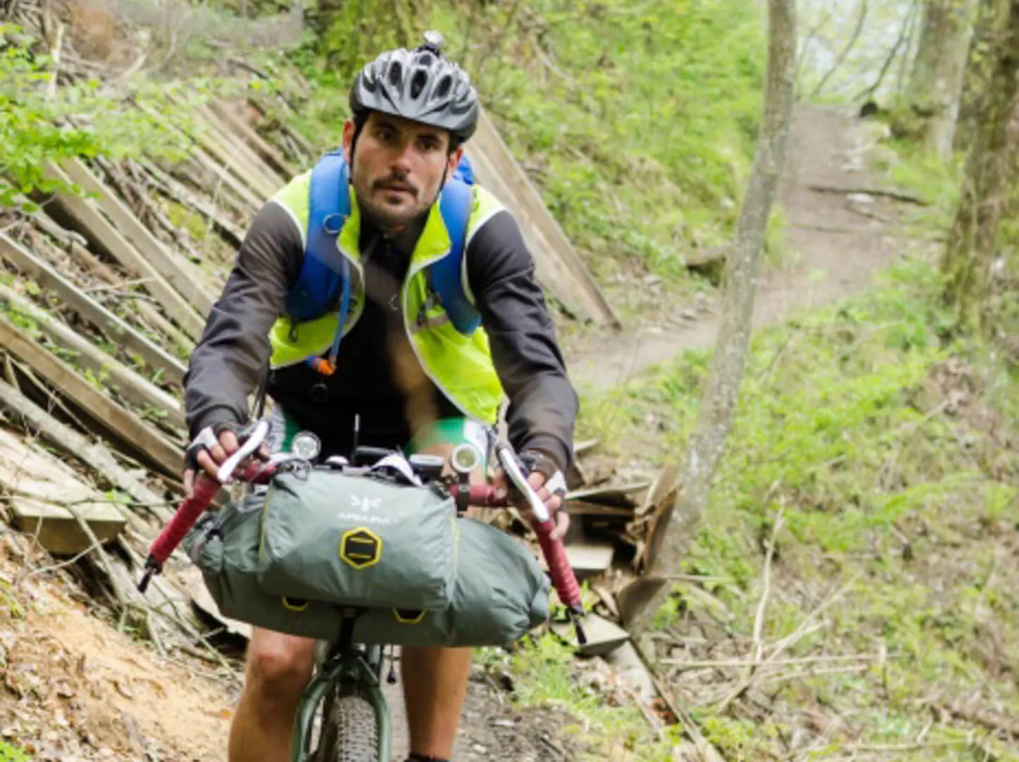 Un rider porta la bici a mano su un sentiero nel bosco
