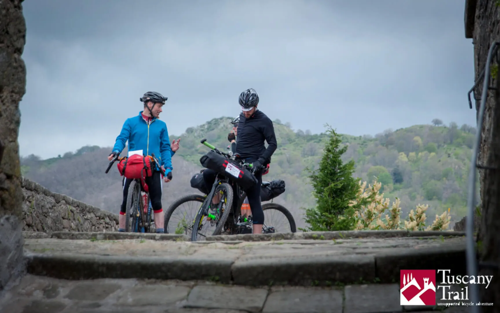 Due rider su un muretto affacciato sulle colline