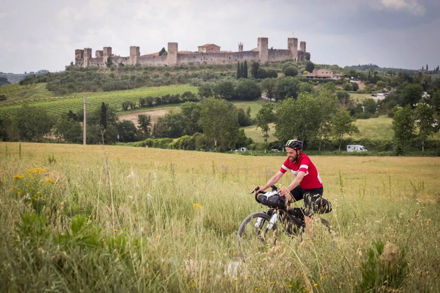 Un rider nei campi sotto le mura di Monteriggioni