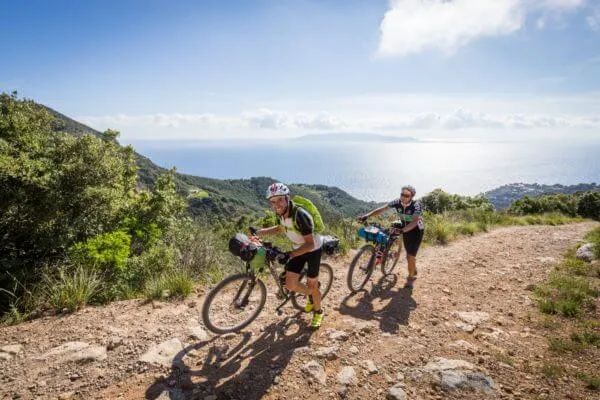 Due rider su uno sterrato con il mare all'orizzonte