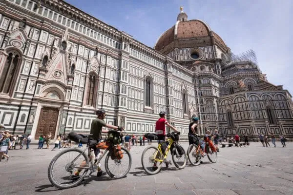 Rider con le bici cariche davanti al Duomo di Firenze