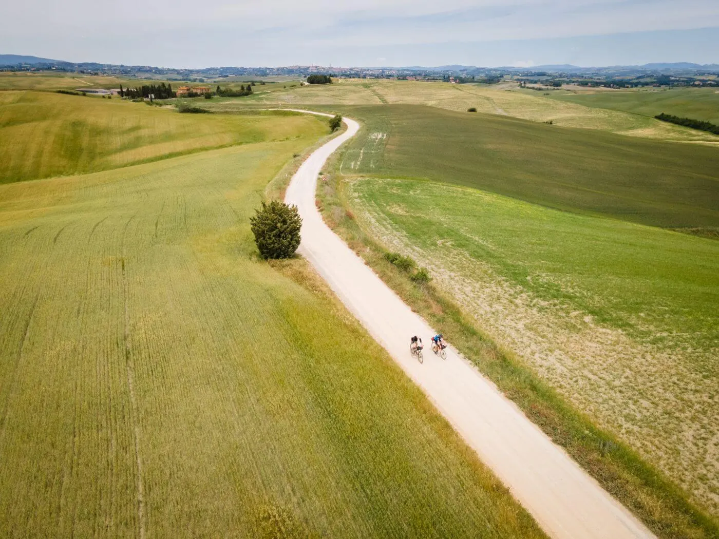 Una strada bianca fra le colline verdi, vista dall'alto