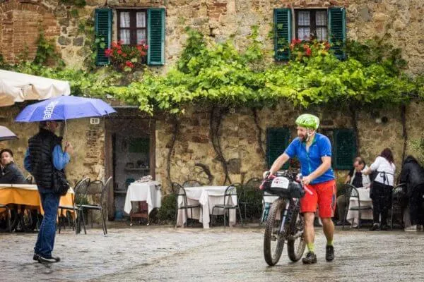 Un rider davanti a una trattoria, sotto la pioggia