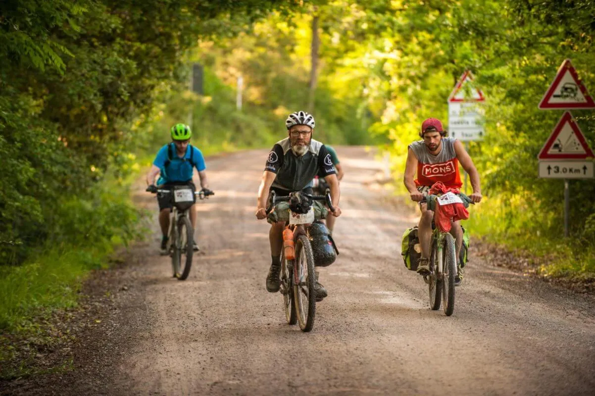 Tre rider su uno sterrato fra gli alberi